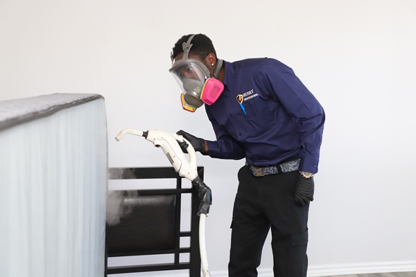 Husky Pest Control technician in full PPE performing pest treatment