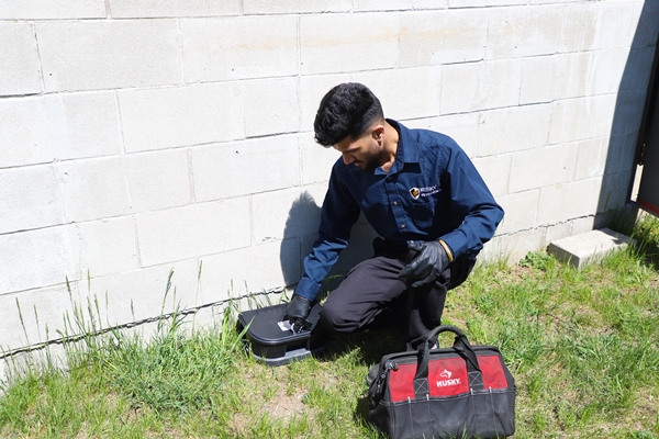 Husky Pest Control technician treating building foundation exterior